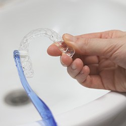 Patient using toothbrush to clean aligner