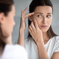 Woman looking in mirror, concerned about wrinkles