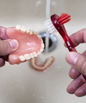 person cleaning their dentures in Jupiter