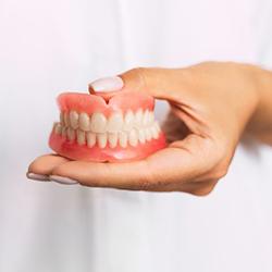 a person holding a pair of dentures