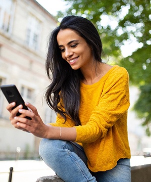 a person smiling and looking at their phone