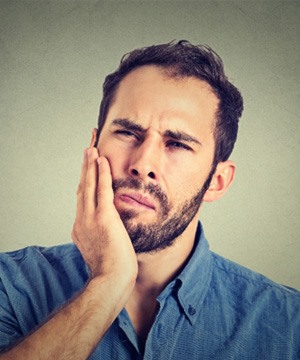 Man with beard rubbing jaw due to discomfort