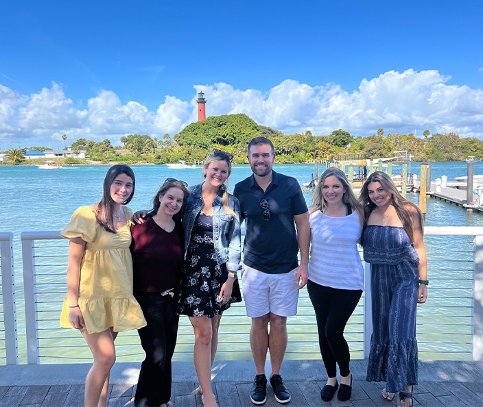 Jupiter dentists and team members standing on dock with lighthouse in background
