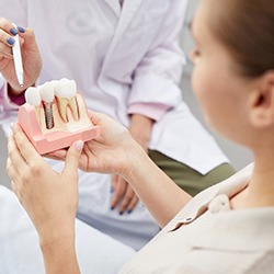 A dental patient holding a dental implant model