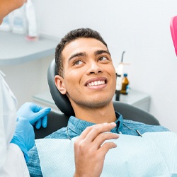 Man smiling while holding dental mirror