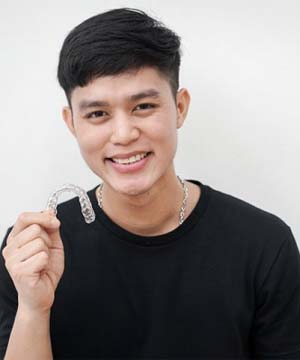 smiling young man holding an Invisalign aligner