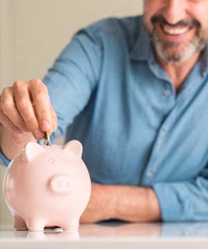 man putting coins into a pink piggy bank