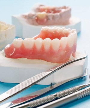 a set of dentures next to a few dental tools
