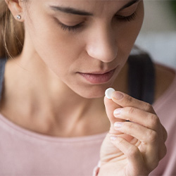 woman taking pain medication for dental implant post-op instructions in Jupiter