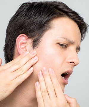 Man in pain holding jaw