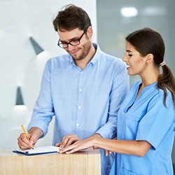 Patient signing paperwork at dental office front desk