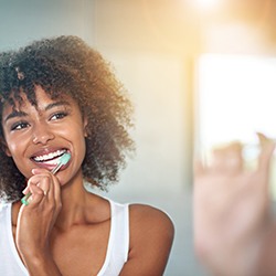 Woman in white tank top brushing teeth
