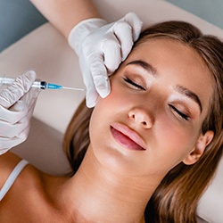 Relaxed woman receiving BOTOX® injection near her TMJ