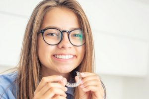 girl holding Invisalign clear aligner