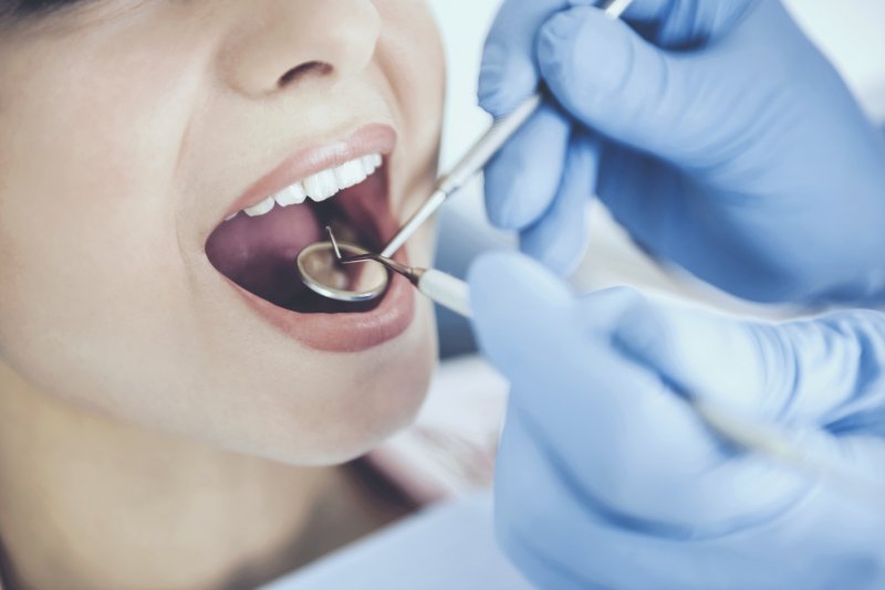 a dentist in Jupiter wearing gloves while examining a patient’s smile