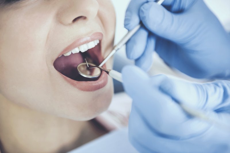 a dentist in Jupiter wearing gloves while examining a patient’s smile 