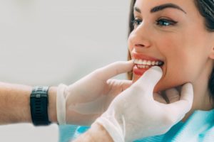 cosmetic dentist examining patient’s teeth