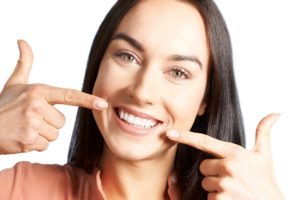 Woman pointing to smile after Invisalign