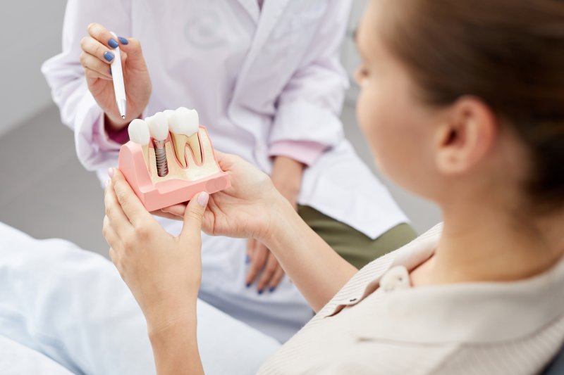 dentist showing their patient a model of a dental implant